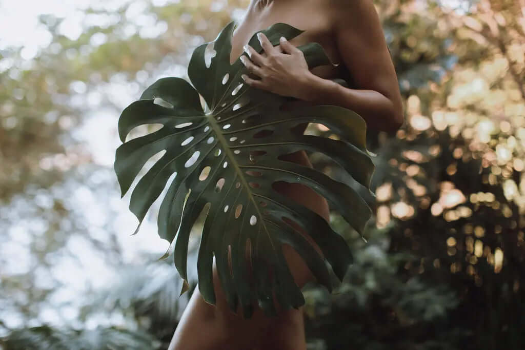 Woman holding a green leaf in natural light, representing collagen cofactors and nutrients that help collagen supplements work better | ATIKA Advanced Skin Nutrition.