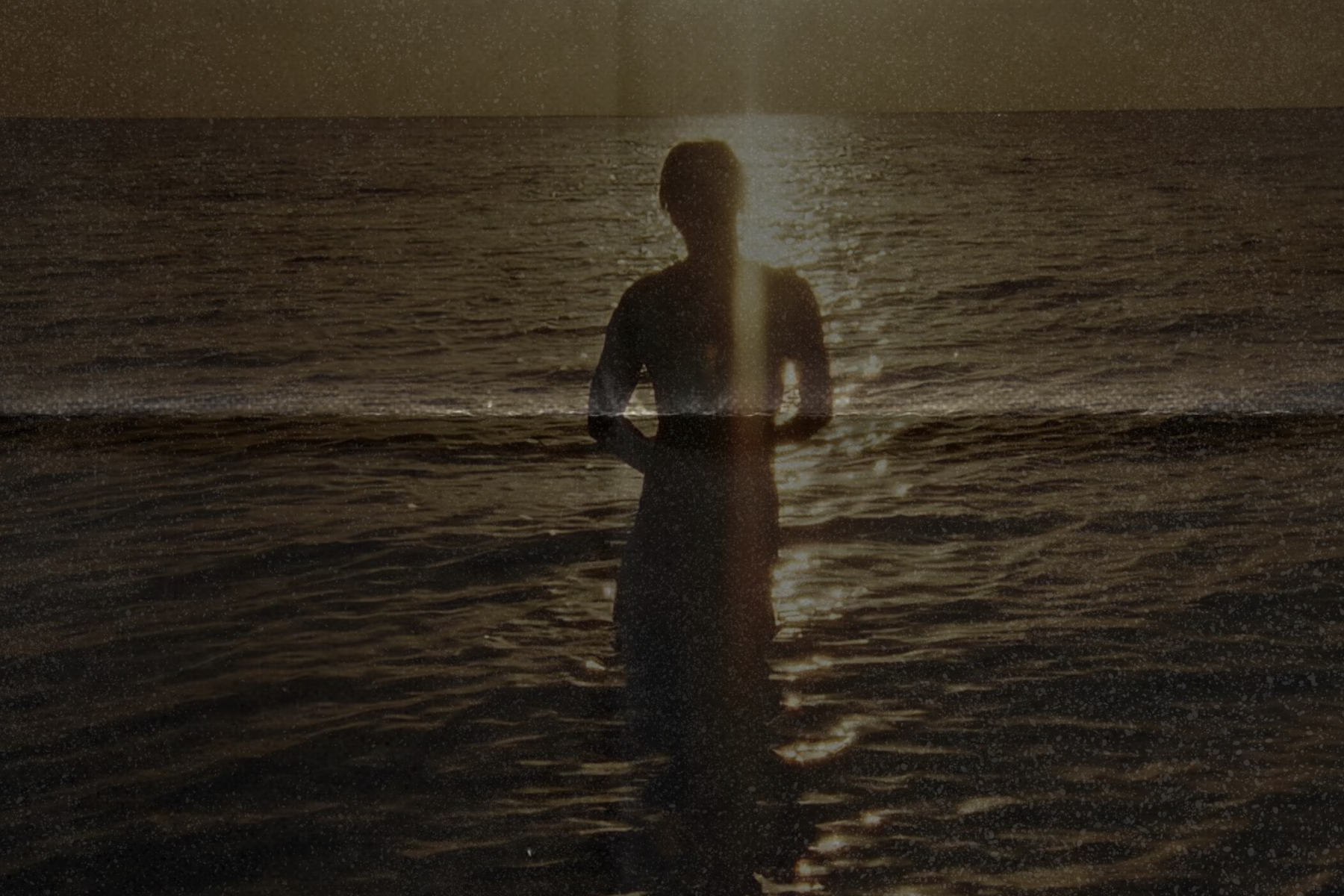 silhouette of woman against sun in a body of water