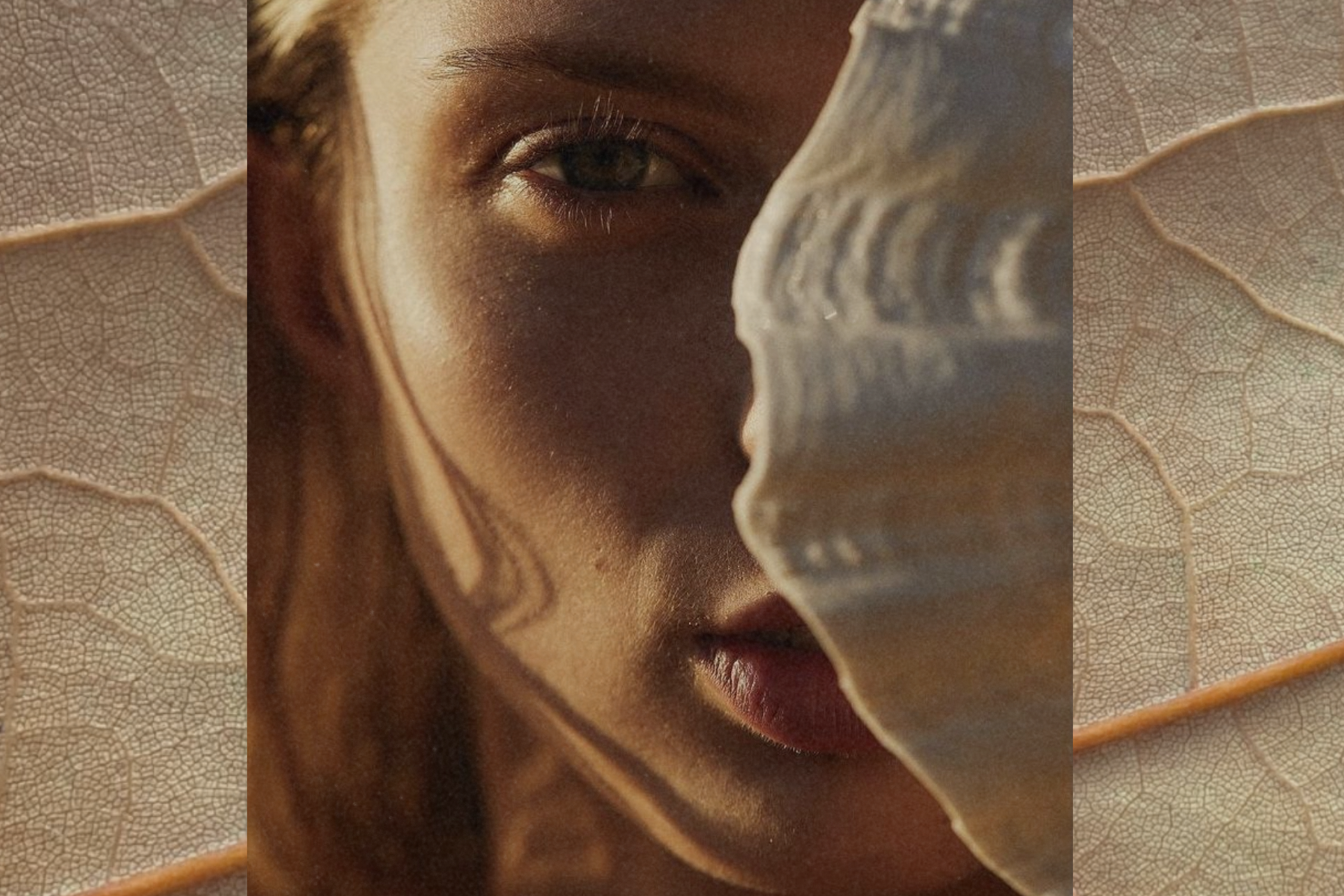 Sunlit close-up of a woman’s face partially veiled by a translucent leaf, warm light and organic textures creating a layered, natural feel.